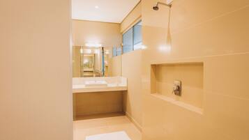 A modern bathroom with a large mirror, a sink, and a shower.