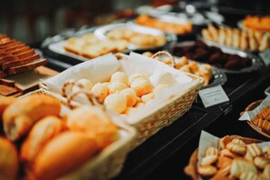 A buffet with various baked goods including bread, pastries, and rolls. - Catuai Hotel (Cacoal)