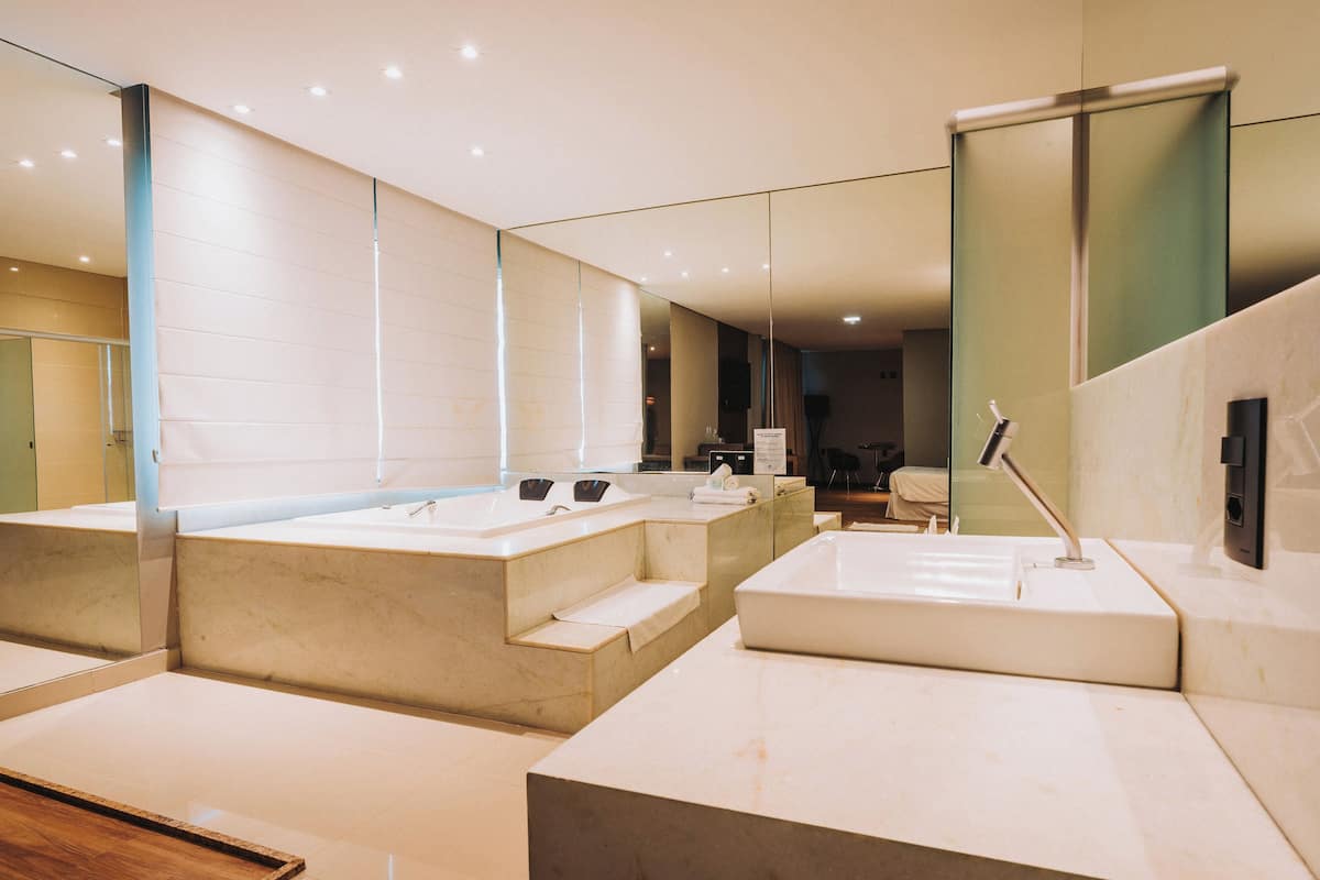 A modern bathroom with two sinks, a large mirror, and a shower area.