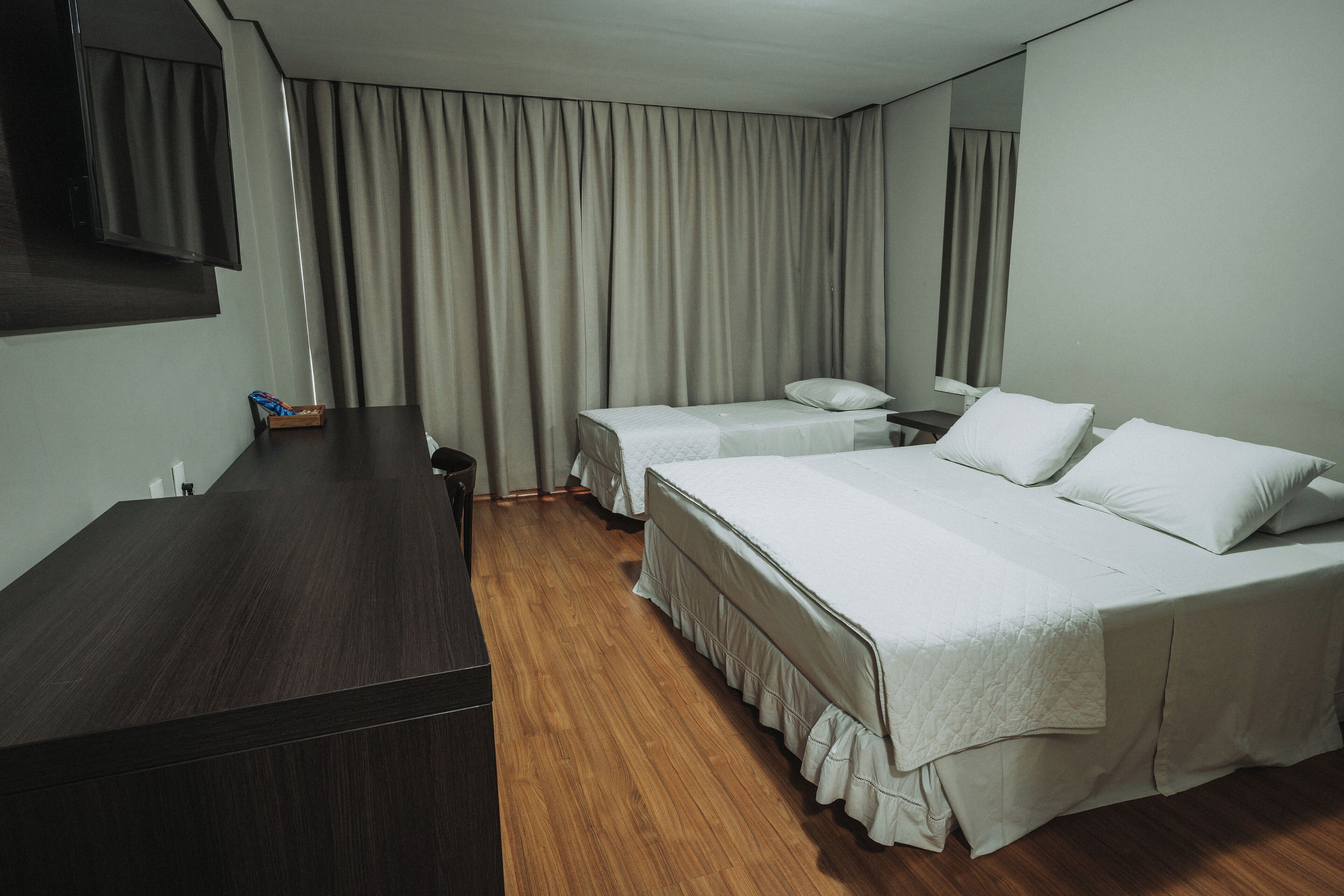 A hotel room with two beds, a desk, and a TV.
