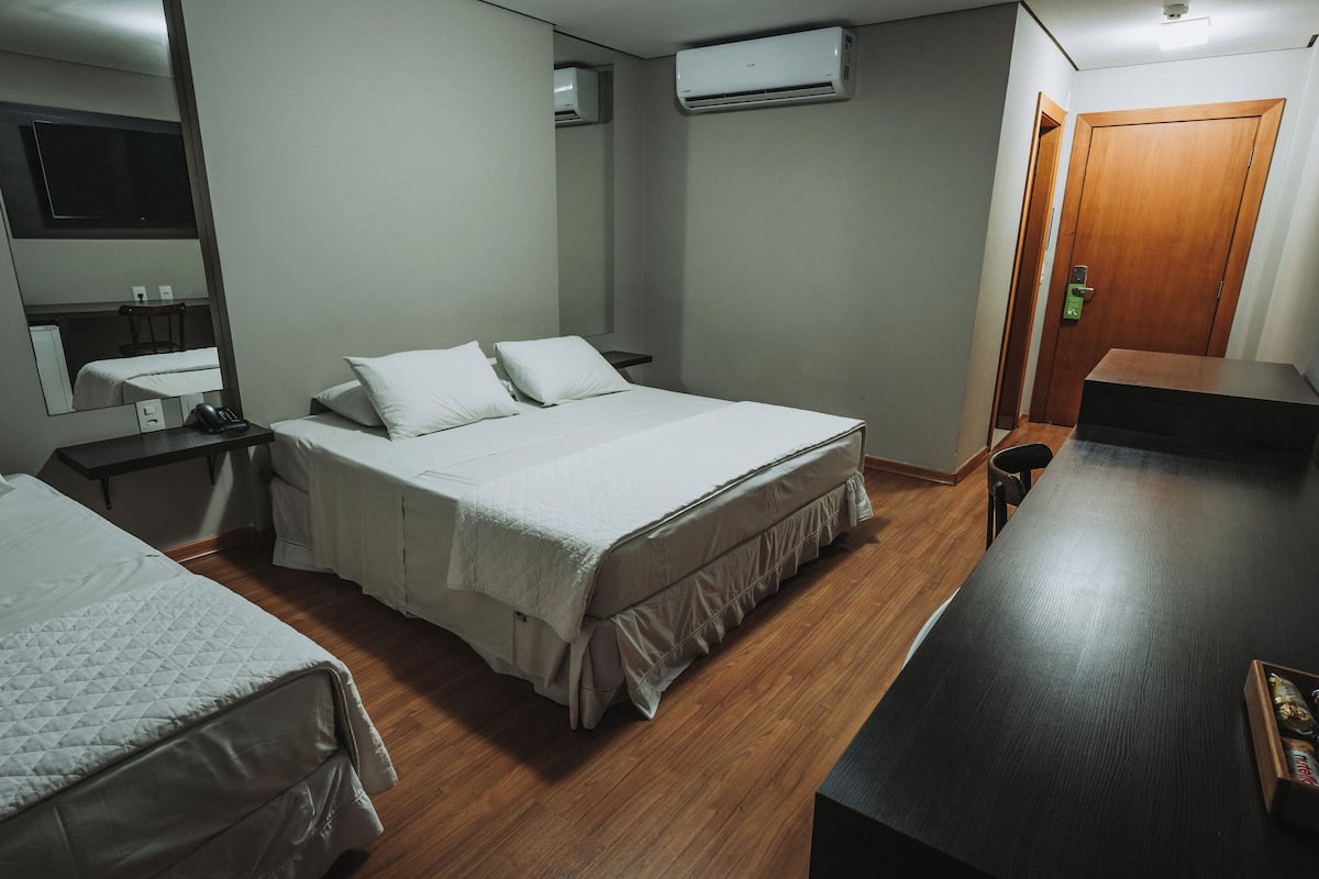 A hotel room with a bed, bedside table, and a desk.