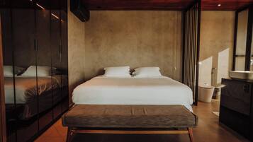 A modern bedroom with a large bed, a bench, and a wardrobe.