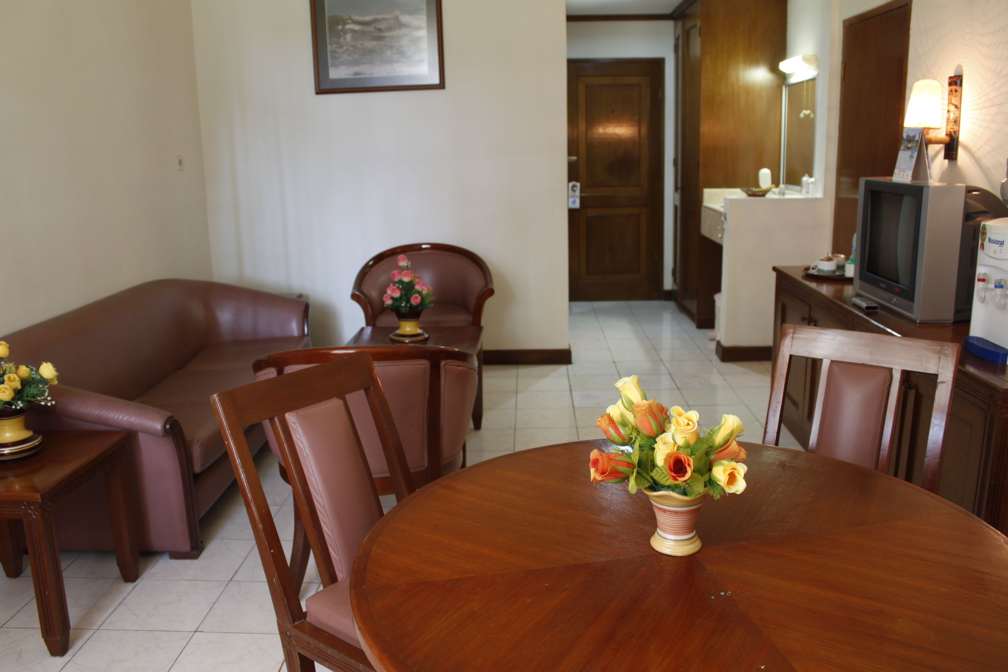 Une chambre d’hôtel dotée d’un coin repas comprenant une table en bois, des chaises et un vase de fleurs.