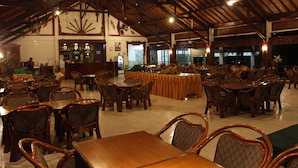 Ein geräumiges Restaurant mit hohen Holzbalkendecken und mehreren Tischen mit Stühlen.