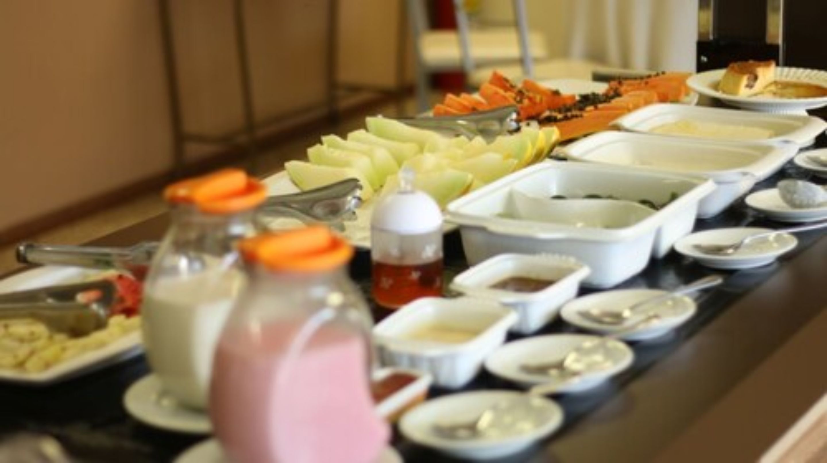 A buffet table with various food items and condiments.