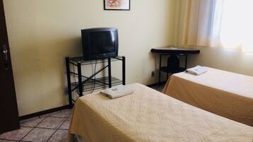 Habitación de hotel con dos camas, un televisor en un mueble bajo, una mesita y un cuadro en la pared.