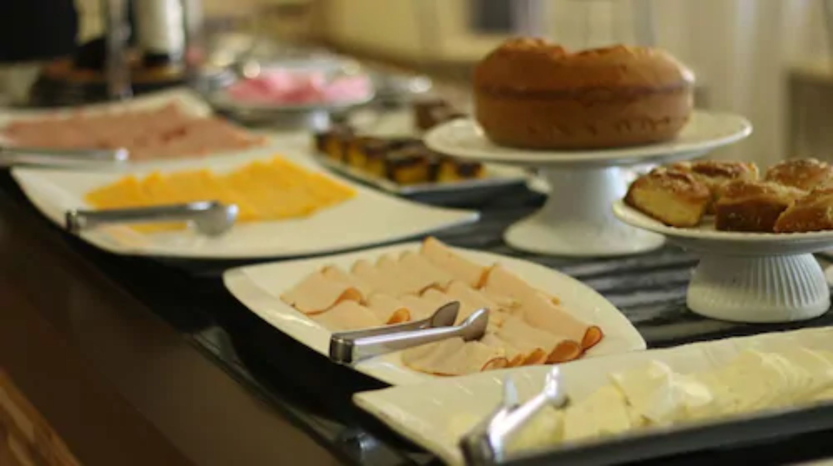 A buffet with various food items including sliced meats, cheeses, and pastries.