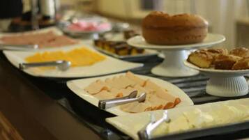 A buffet with various food items including sliced meats, cheeses, and pastries.