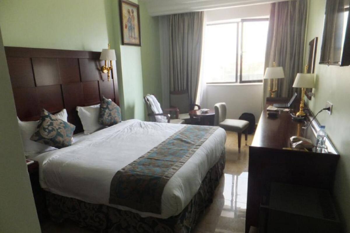 Quarto de hotel com uma cama grande, uma escrivaninha e uma cadeira.