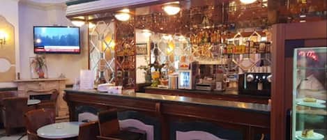 A bar area with a counter, chairs, and a television screen.