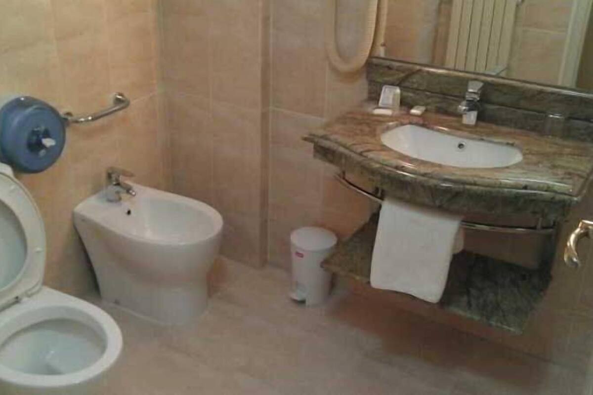 Casa de banho com sanita, bidé, lavatório e espelho.