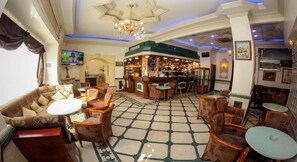 A hotel lobby with a bar area, seating arrangements, and a chandelier. - Hotel El Kenz (Setif)
