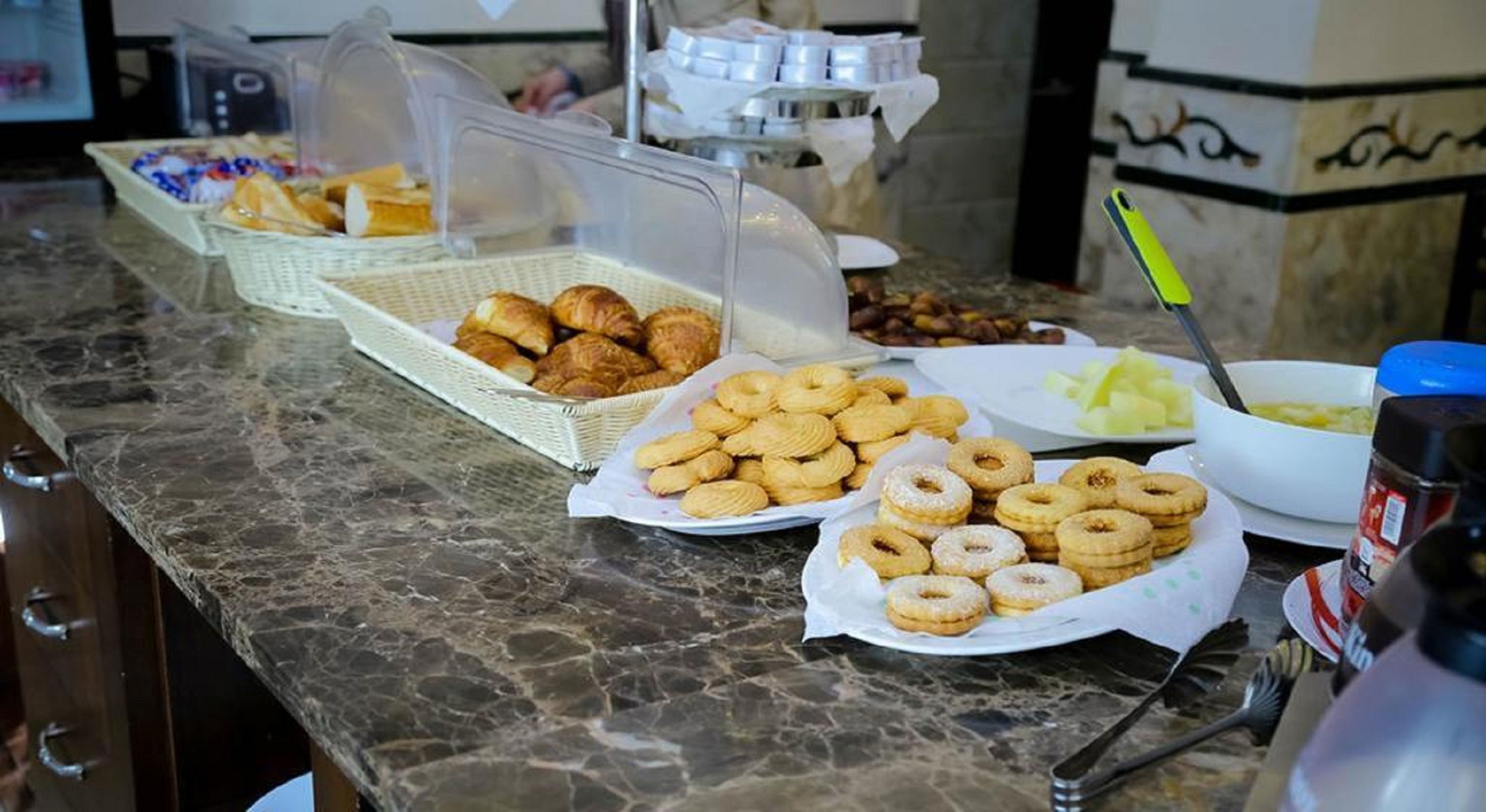 A buffet table with various pastries and a bowl of soup.