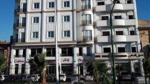 Un hotel de varios pisos con fachada blanca, balcones y un restaurante en la planta baja.