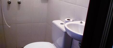 Un baño pequeño y funcional con inodoro, bidé y lavamanos.