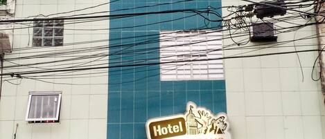 Un bâtiment d’hôtel avec une entrée rouge, de nombreuses fenêtres et des câbles électriques apparents.