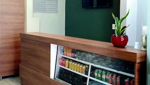 Een receptiegedeelte met een houten balie, een potplant en een drankkoelkast.