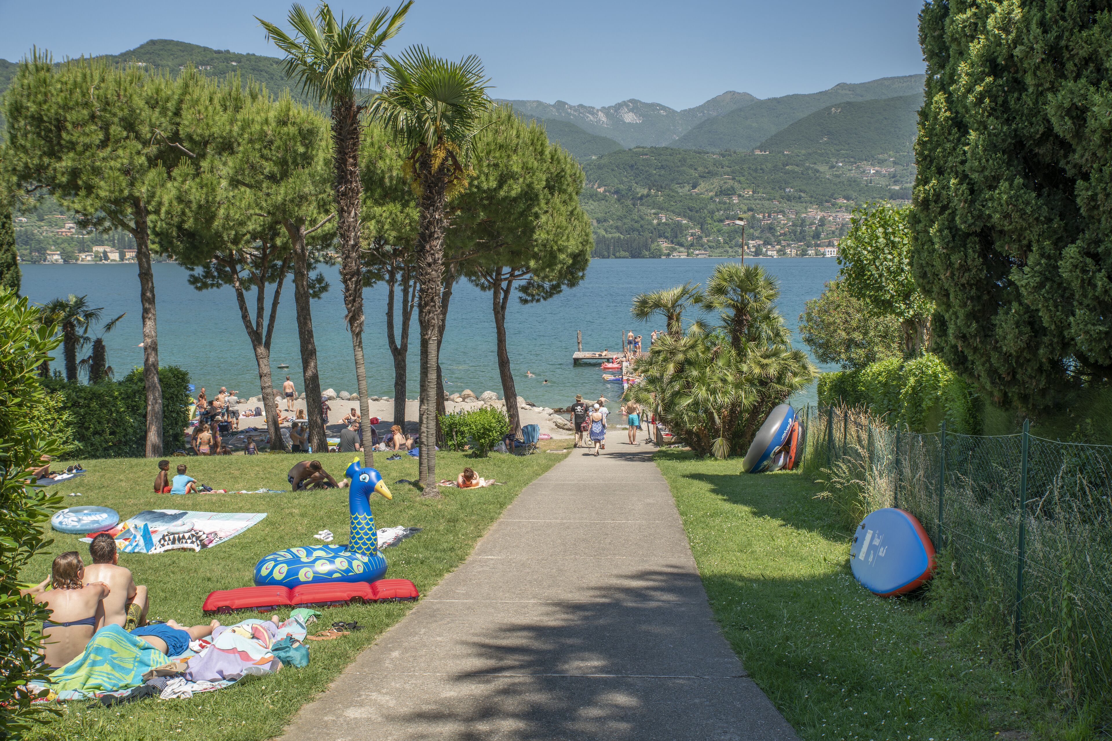 Un sentier menant à une plage où l’on trouve des jeux gonflables et où les gens se détendent.