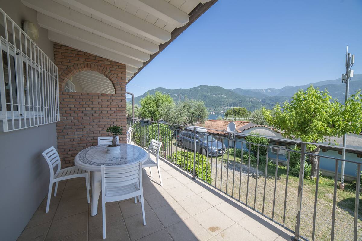 Ein Balkon mit Tisch und Stühlen, einem Blumentopf und Blick auf ein Gebirge.