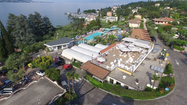 Vista aérea de un resort con piscina, mobiliario exterior y vistas al lago.