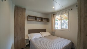 Un dormitorio con cama, un armario de madera, una mesita de noche y una ventana con cortinas.
