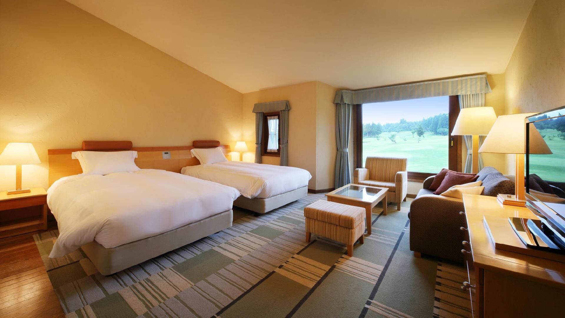 A hotel room with two beds, a sofa, a TV, and a view of a golf course.