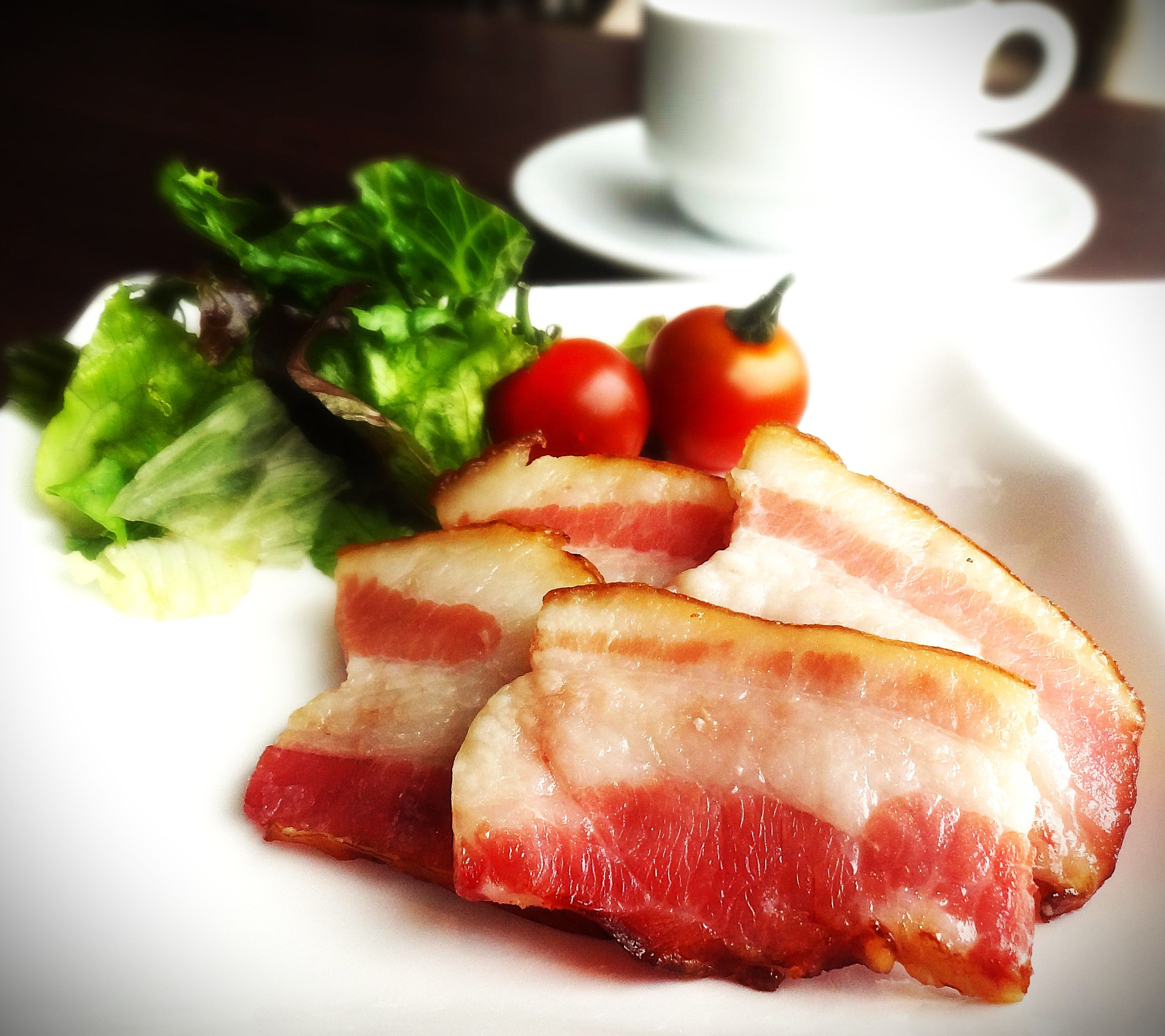 A plate with bacon, lettuce, and cherry tomatoes.