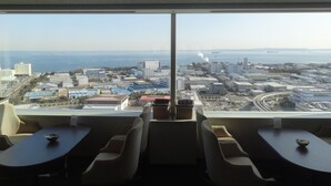 Habitación de hotel en un rascacielos con un amplio ventanal que da a una vista panorámica de la ciudad y el mar.