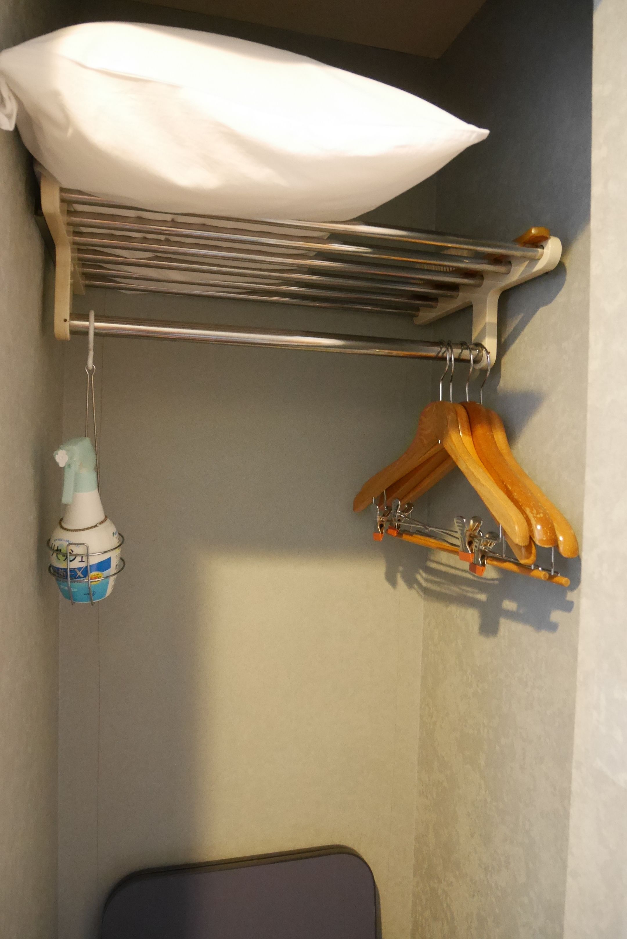 A metal drying rack with a white cloth and wooden hangers.