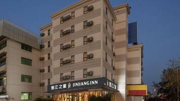 A multi-story hotel with a prominent signage, a parking lot, and a clear sky.