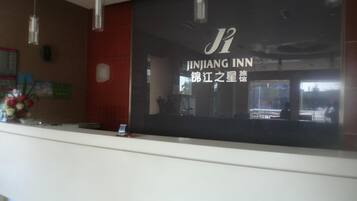 A reception desk with a sign for Jinjiang Inn, featuring a modern design with pendant lighting.