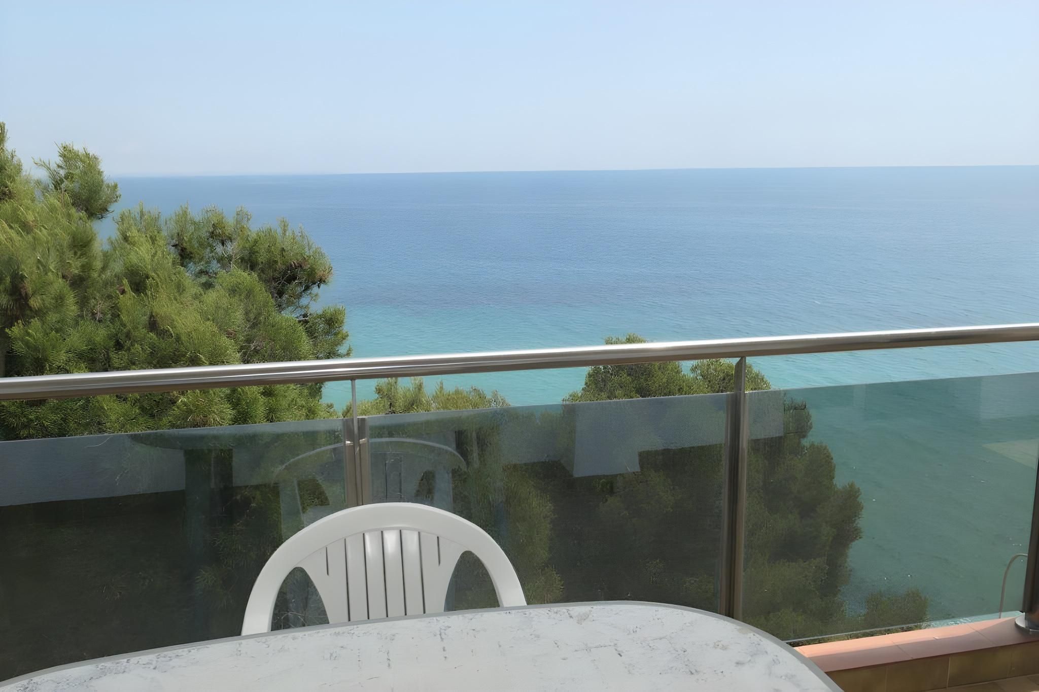 Un balcón con vista despejada al mar y a los árboles.