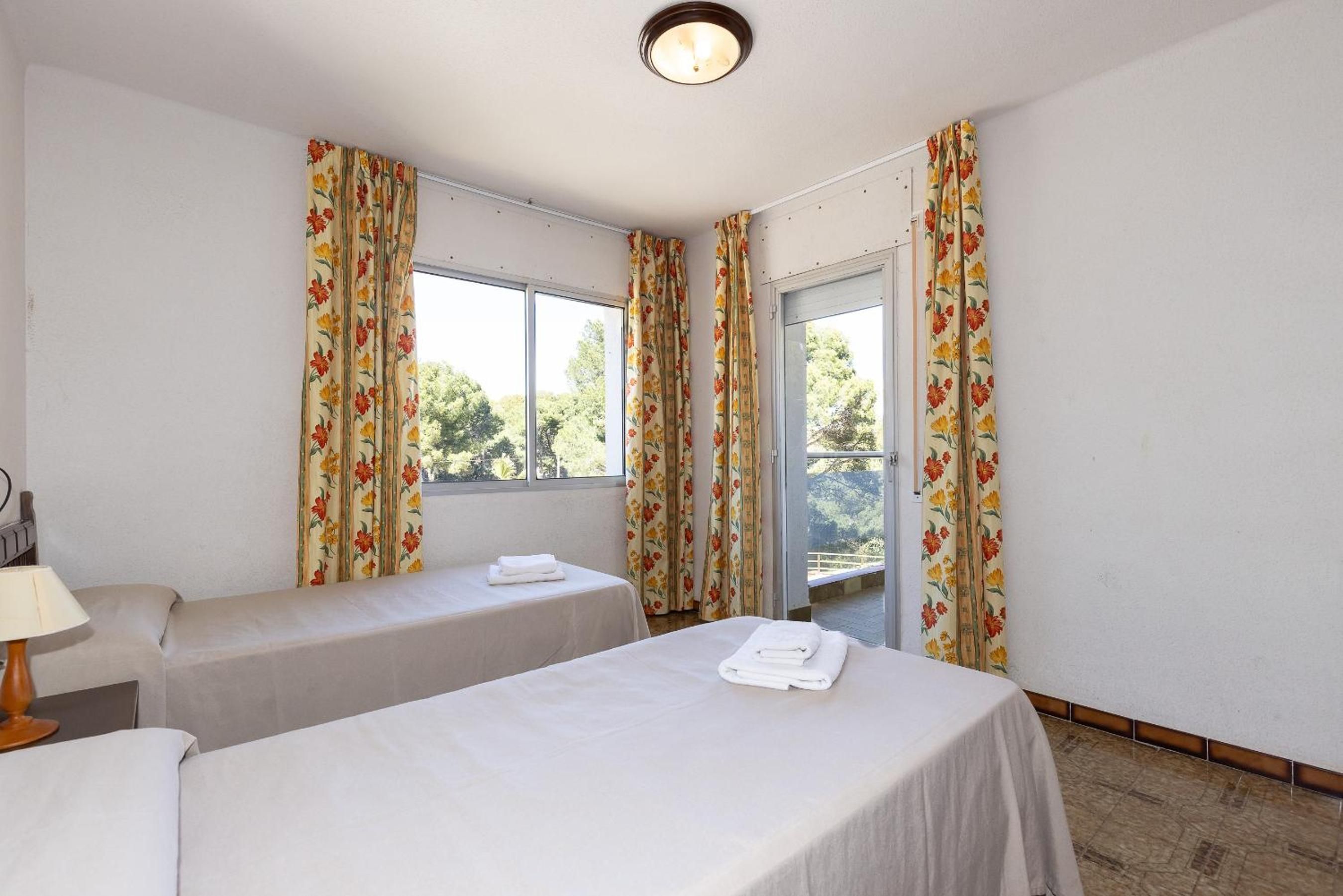 Una habitación con dos camas, una ventana y cortinas.
