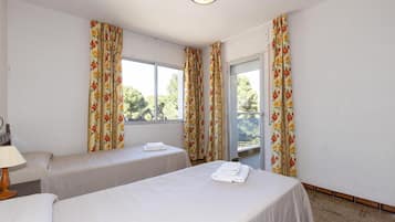 Una habitación con dos camas, una ventana y cortinas.