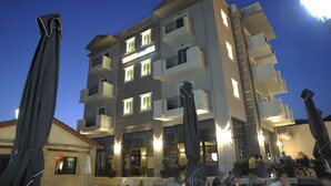 Um hotel de vários andares com varandas, área de estar ao ar livre e fachada bem iluminada.