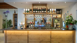 A bar area with a wooden counter, shelves of bottles, and glasses. - Seehotel Schlick (Fuschl am See)