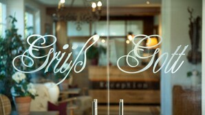 A cozy interior with a reception desk, comfortable seating, and a chandelier. - Seehotel Schlick (Fuschl am See)