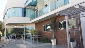 Un hôtel moderne doté d’une façade en verre, d’un escalier menant à l’entrée et d’une enseigne indiquant « HÔTEL TURIS ».