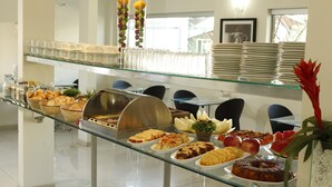 Un buffet proposant une variété de plats, un coin café et une vitrine où sont exposées des assiettes.