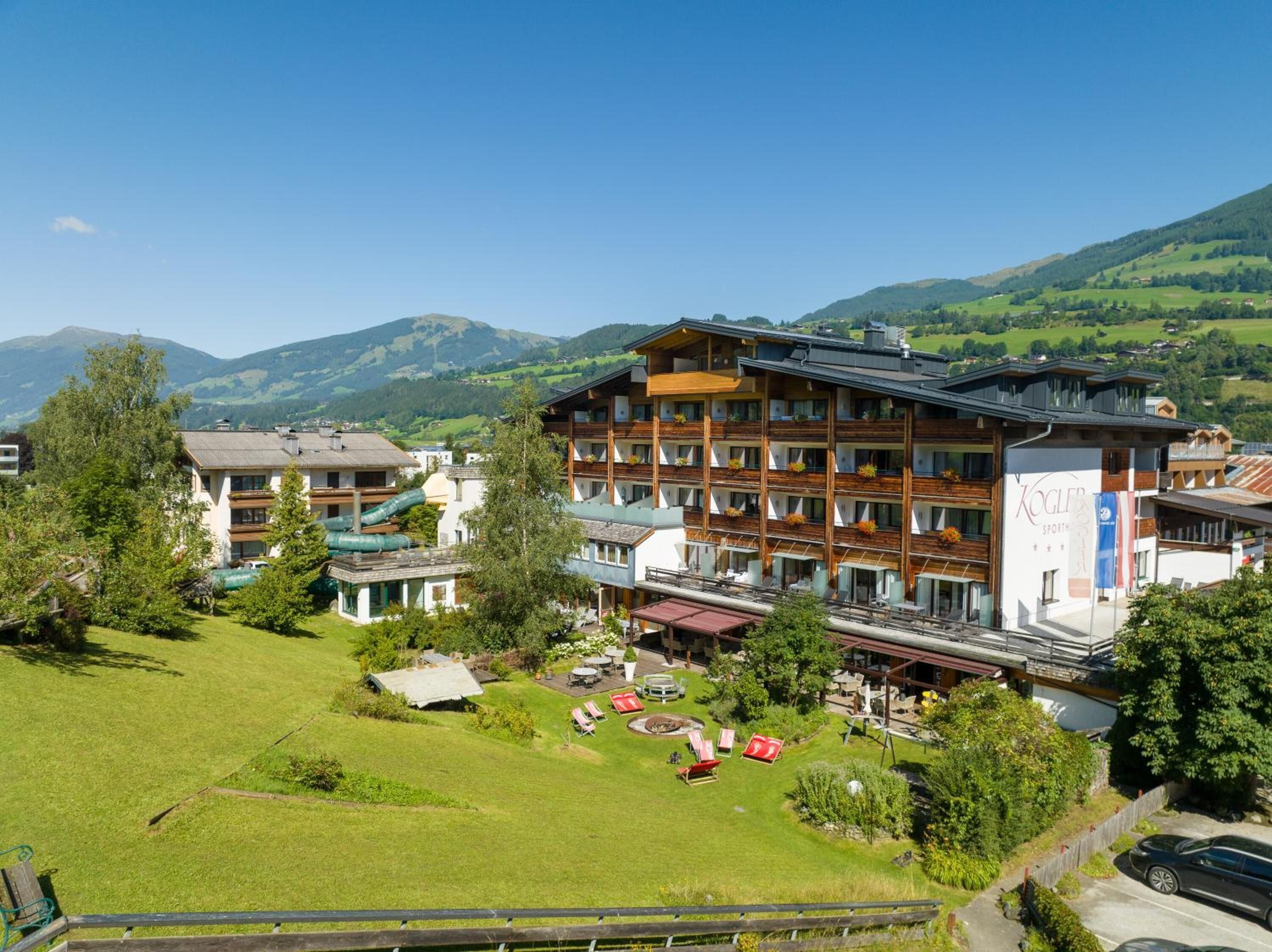 A hotel with multiple floors, outdoor seating, and a view of mountains.
