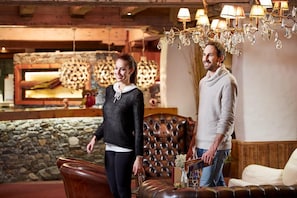 A lobby with a stone wall, a fireplace, and a chandelier. - Sporthotel Kogler (Mittersill)