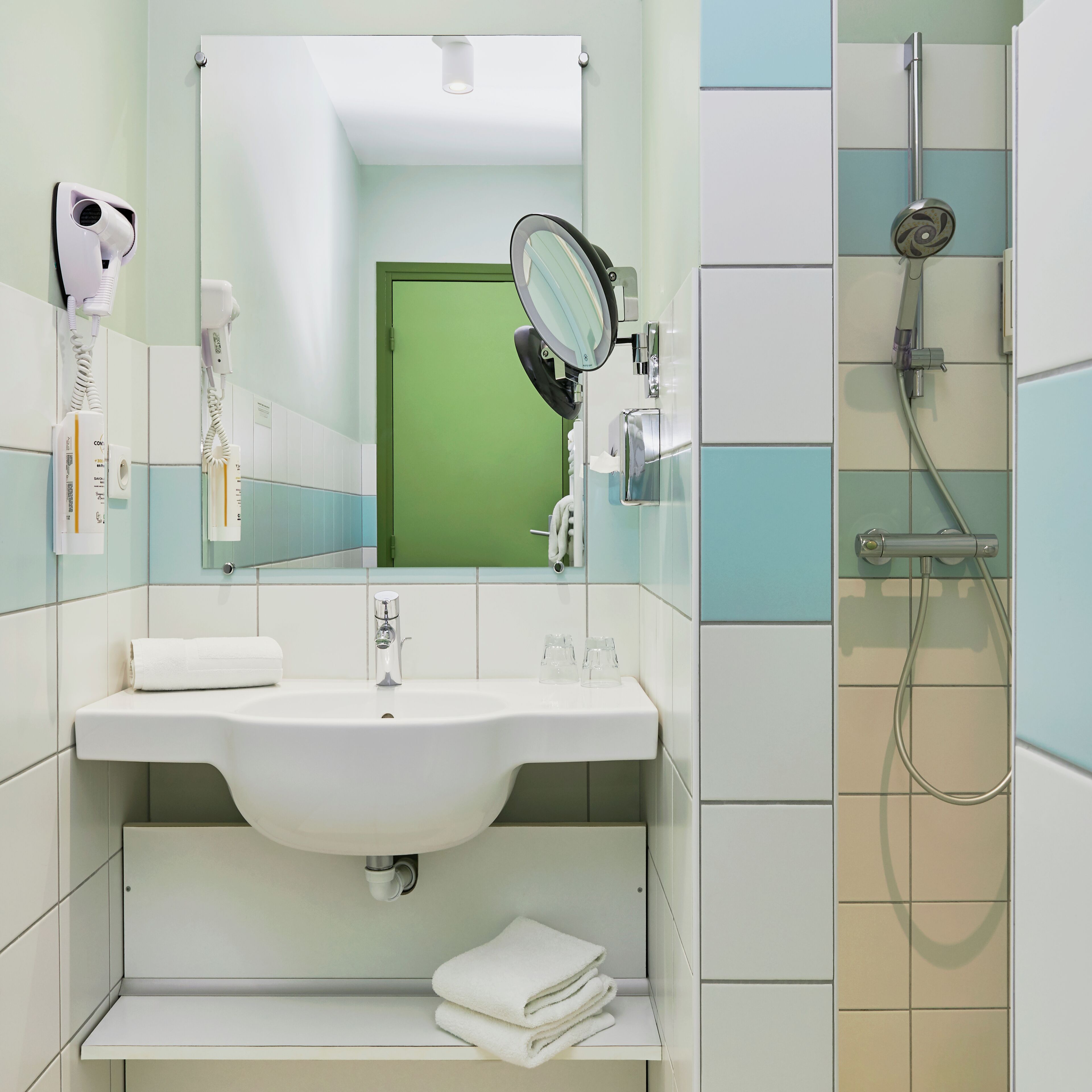 Ein Badezimmer mit Waschbecken, Spiegel, Handtuchhalter und Dusche.
