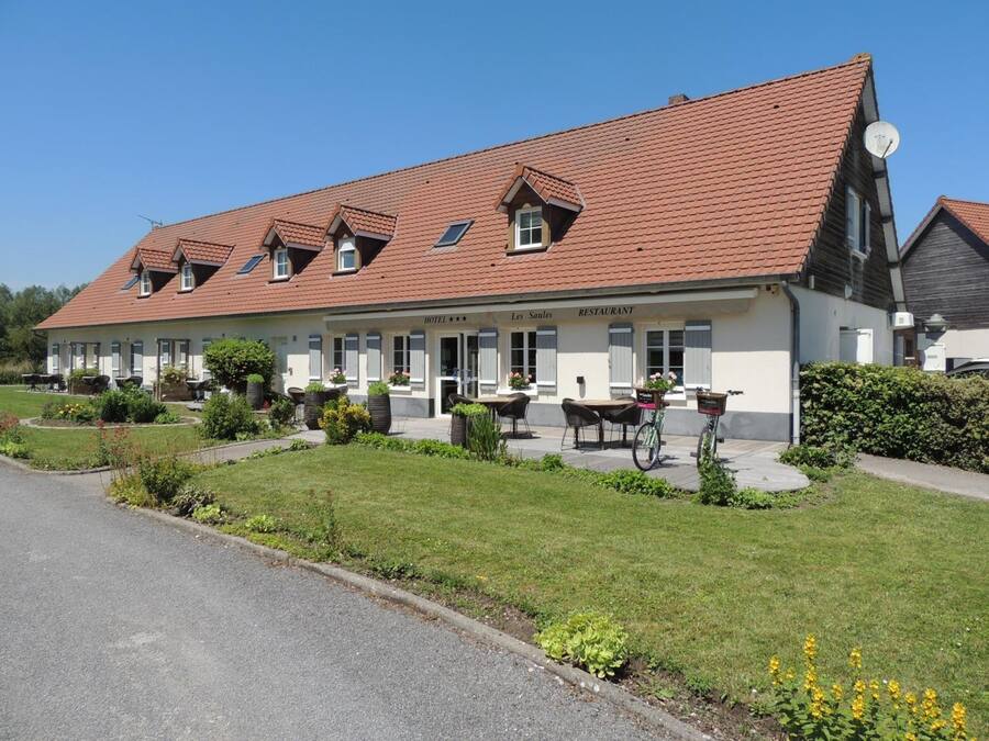 A hotel with a red-tiled roof, multiple windows, outdoor seating, and a garden area.