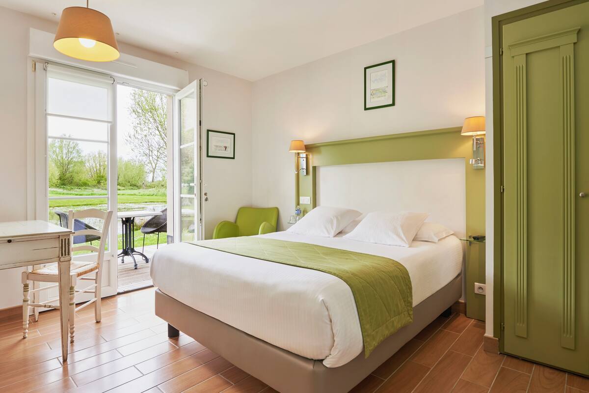 Une chambre à coucher avec un lit, un bureau et une chaise. Il y a une porte et une fenêtre.