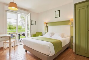 A bedroom with a bed, a desk, and a chair. There is a door and a window. - Hôtel Spa & Restaurant Les Saules (Favieres)