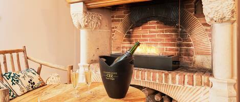 Una chimenea de ladrillo con una botella de champán y una copa sobre una mesa de madera.