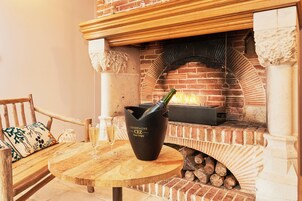 Una chimenea de ladrillo con una botella de champán y una copa sobre una mesa de madera.