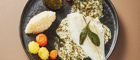 A plate with rice, fish, and vegetables on a textured surface.