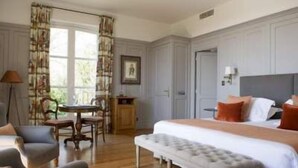 A hotel room with a large bed, a small table, a chair, and a bench. - Domaine de la Tortinière (Veigne)