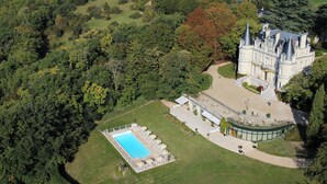 An aerial view of a large estate with a swimming pool, manicured lawn, and a grand building with multiple towers. - Domaine de la Tortinière (Veigne)